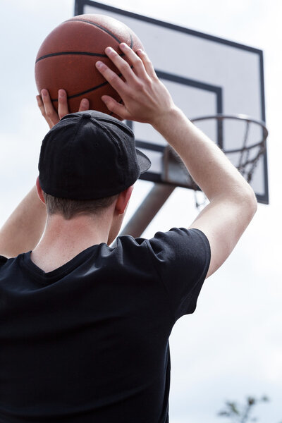 Male aiming basketball at hoop