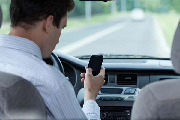 Man skicka SMS på mobiltelefon under bilkörning — Stockfoto