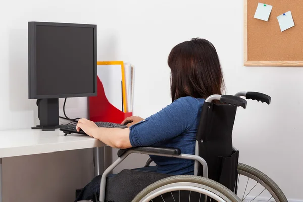 Mujer en silla de ruedas trabajando en la oficina — Foto de Stock