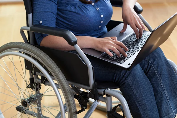 Woman on a wheelchair with laptop — Stock Photo, Image