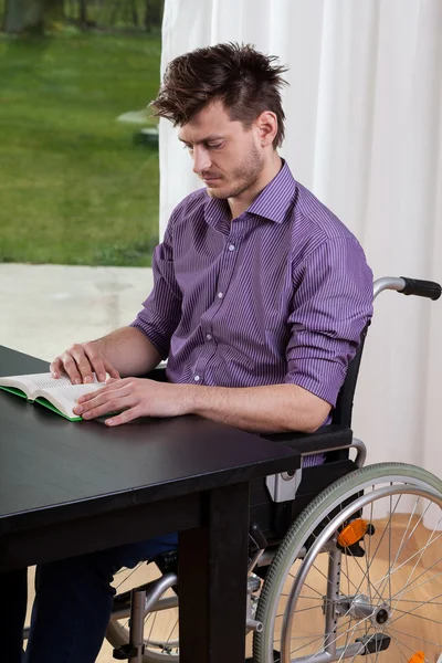 Man på rullstol läser en bok — Stockfoto