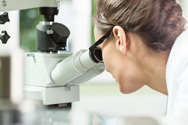 Vrouw die met Microscoop werkt — Stockfoto