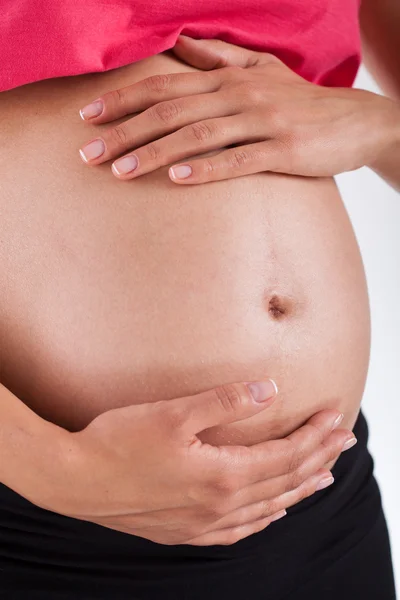 Mulher grávida segurando barriga em suas mãos — Fotografia de Stock