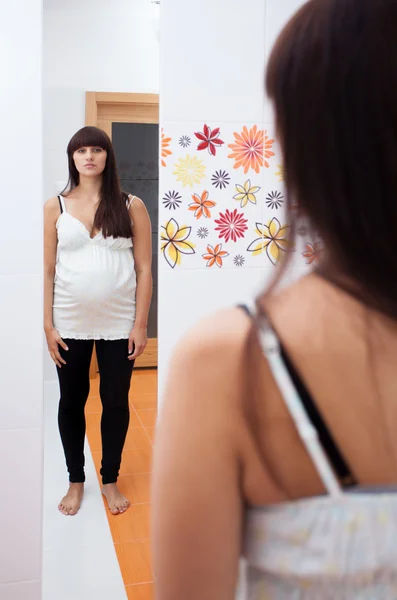 Pregnant woman looking in mirror — Stock Photo, Image