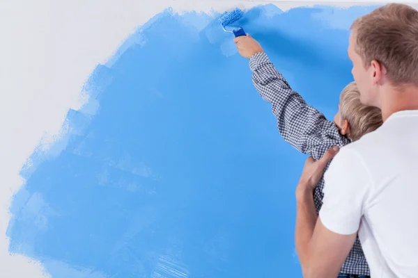 Baba oğlunu duvar boyama sırasında yükseltme — Stok fotoğraf