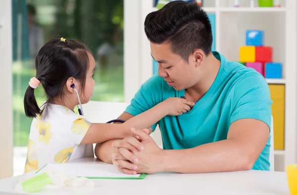 Asian girl examining her father — Stock Photo, Image