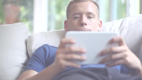 Ung man spendera fri tid med tablett och avkopplande film — Stockvideo