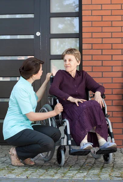 Infirmière parlant avec une femme âgée en fauteuil roulant — Photo