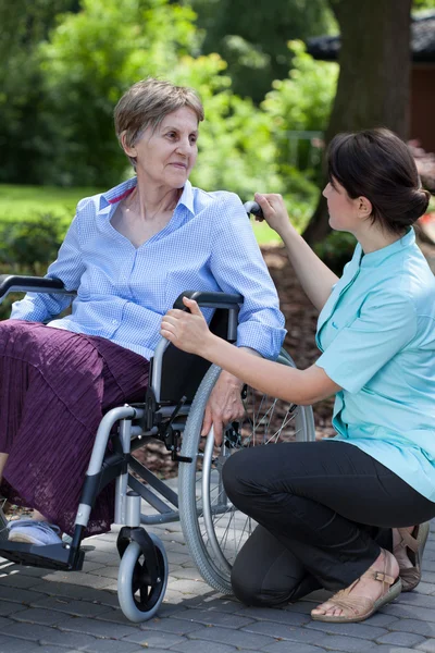 Female caregiver talking with handicapped woman on wheelchair — Stock Photo, Image