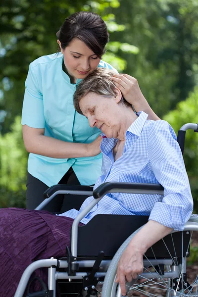 Infirmière réconfortant une vieille femme en fauteuil roulant — Photo