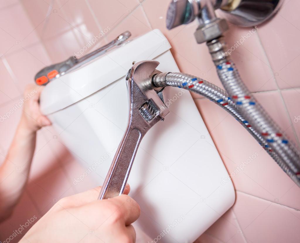 Plumber fixing toilet with wrench