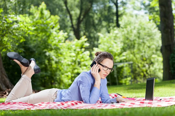 Woman lying on blanket working — Stock Photo, Image