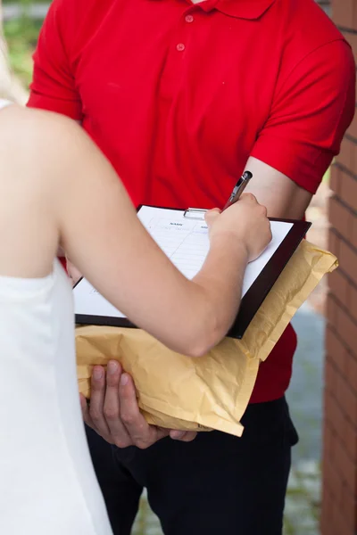 Woman signing package delivery papers — Stock Photo, Image
