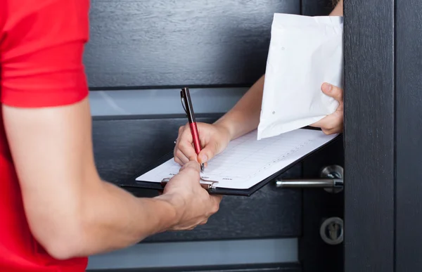 Vrouw ondertekening pakket levering papers — Stockfoto