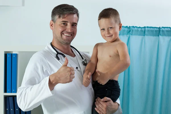Pediatra alegre segurando menino nos braços — Fotografia de Stock