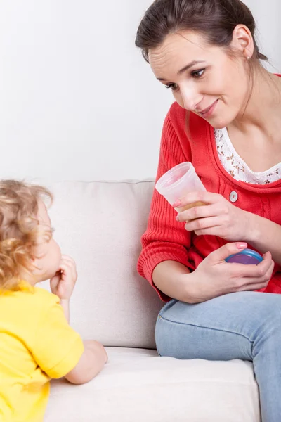 Mum giving syrup to son — Stock Photo, Image