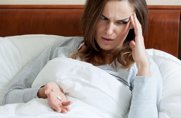 Woman with headache in bed — Stockfoto