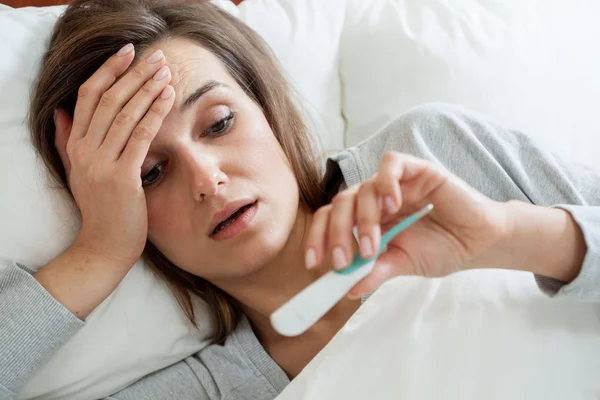 Mujer con fiebre en la cama — Foto de Stock