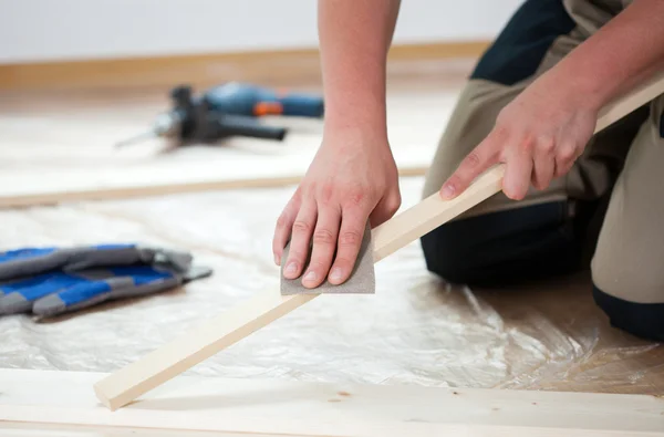 Using sandpaper for polishing wooden plank — Stock Photo, Image