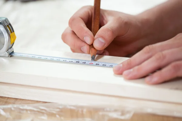 Male hands using measuring tape on wooden board — Stock Photo, Image