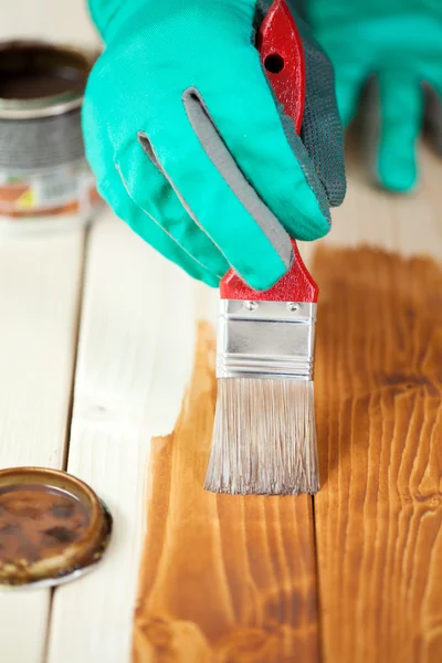 Manos en guantes protectores pintura tablero de madera — Foto de Stock