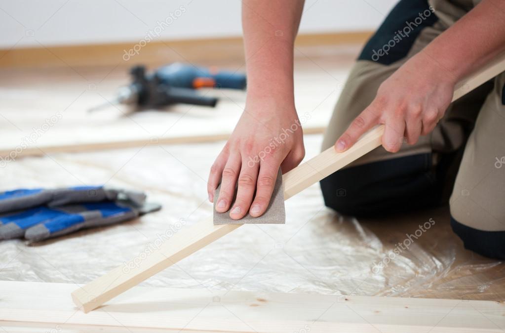 Using sandpaper for polishing wooden plank