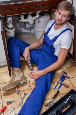 Lavabo onarım sırasında yorgun adam