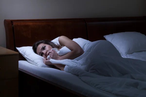 Mulher aterrorizada deitada na cama — Fotografia de Stock