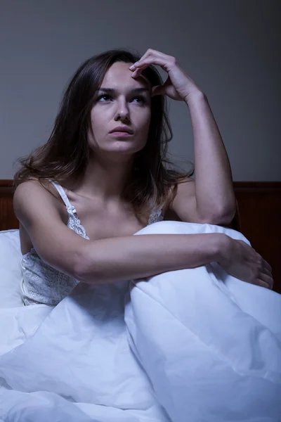 Nachdenkliche Frau sitzt im Bett — Stockfoto