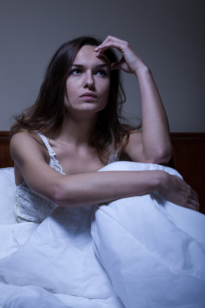 Thoughtful woman sitting in bed