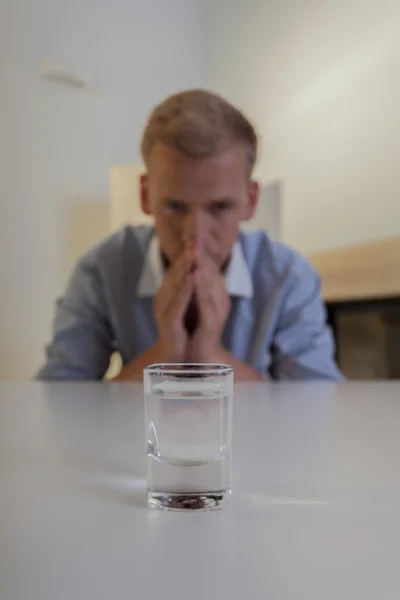 Uomo e un bicchiere di vodka sul tavolo — Foto Stock