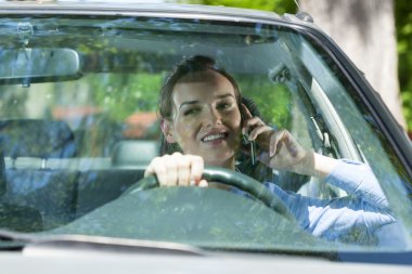 Kadın bir araba sürüş sırasında cep telefonu arama