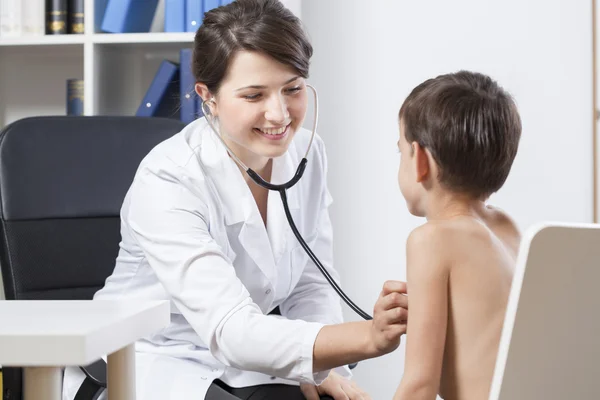 Smiling young female doctor examining little boy — Stock Photo, Image