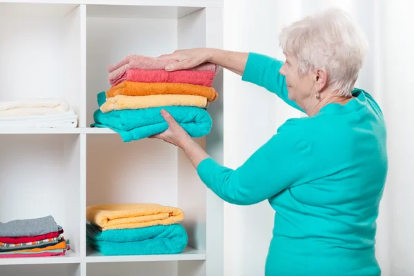 Mujer poniendo toallas en el estante — Foto de Stock