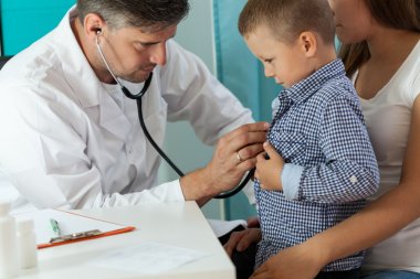 Pediatrician examining boy lungs  clipart