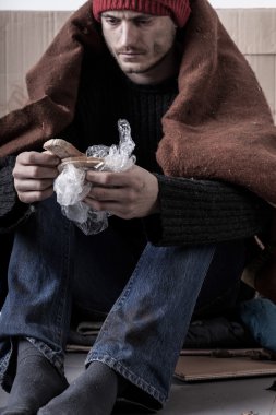 Soğuk ve hüzünlü evsiz adam bir ekmek yiyor 