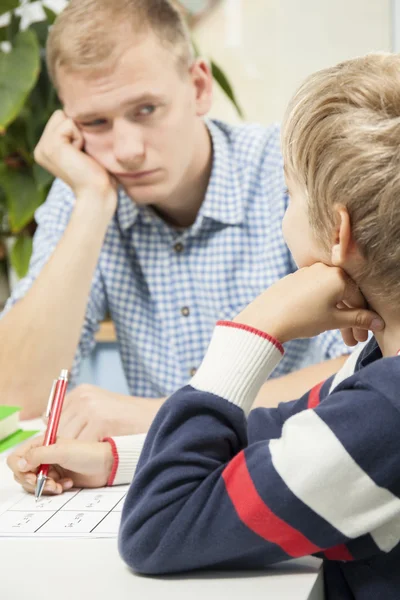 Padre annoiato aiutare il figlio con i compiti — Foto Stock