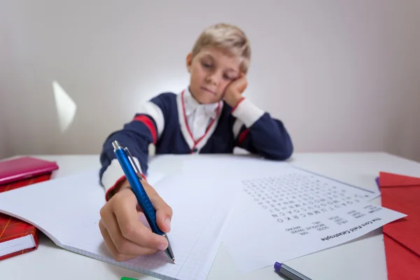 Gelangweilter Junge schreibt in Notizbuch — Stockfoto