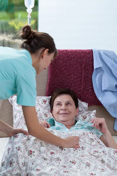 Bedridden woman and helpful nurse — Stock Photo, Image