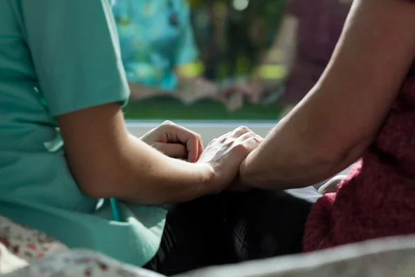 Sjuksköterska och kvinna sitter på sängen — Stockfoto