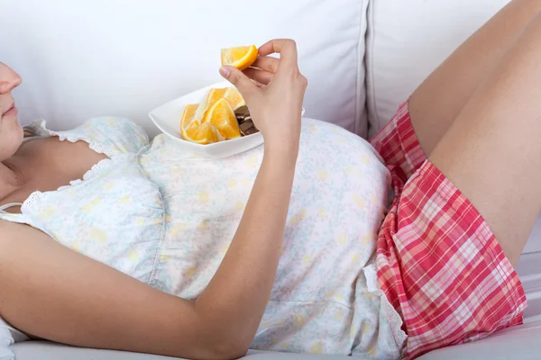 Kobieta w ciąży jedzenia pomarańczy — Zdjęcie stockowe