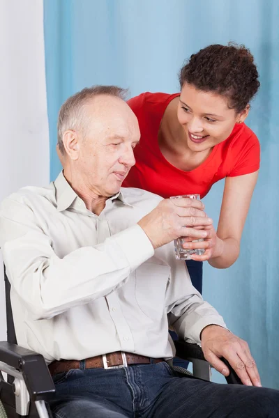 Νοσοκόμα δίνει άτομα με ειδικές ανάγκες άτομο ποτήρι νερό — Φωτογραφία Αρχείου