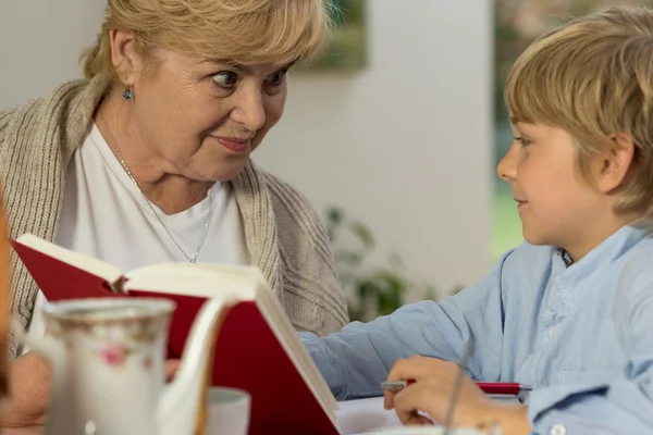 Senior babysitter caring about schoolboy — Stock Photo, Image