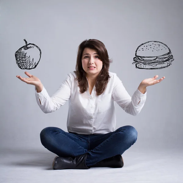 Girl with a dilemma about food — Stock Photo, Image
