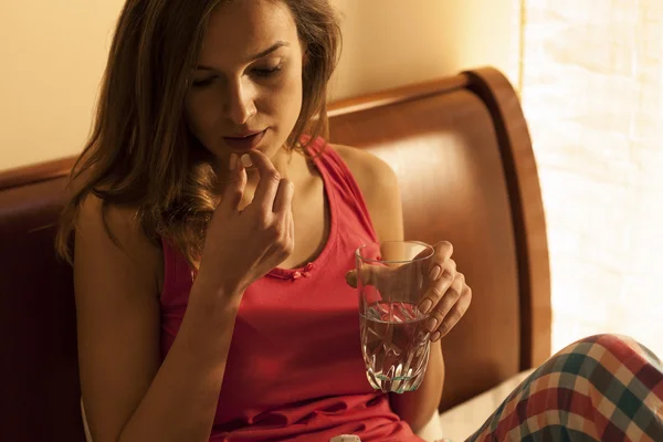 Женщина в пижаме принимает таблетки — стоковое фото