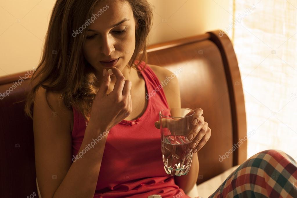 Woman in pyjamas taking pill