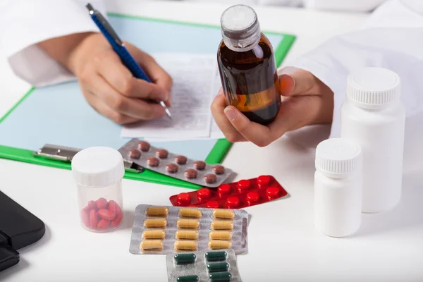 Le mani del medico che prescrivono sciroppo — Foto Stock