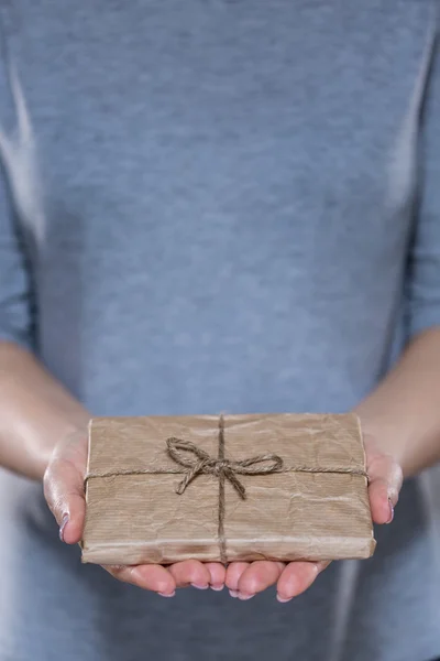 Vrouwelijke handen met eenvoudige verpakte gift — Stockfoto