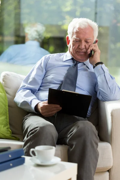 Oudere zakenman zitten in een leunstoel — Stockfoto