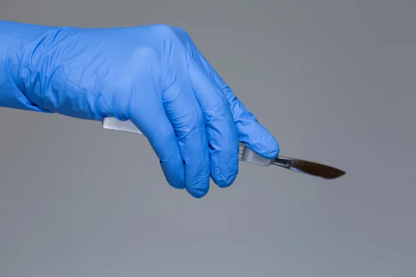 Doctor in gloves holding a scalpel — Stock Photo, Image